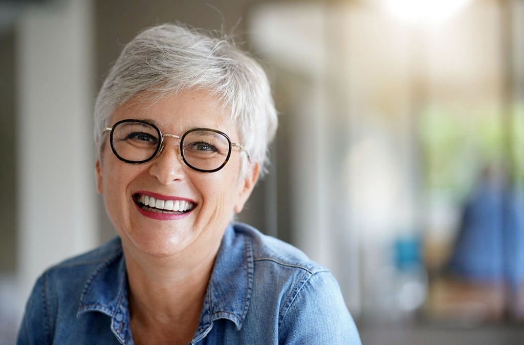 Woman smiling after receiving dental implants