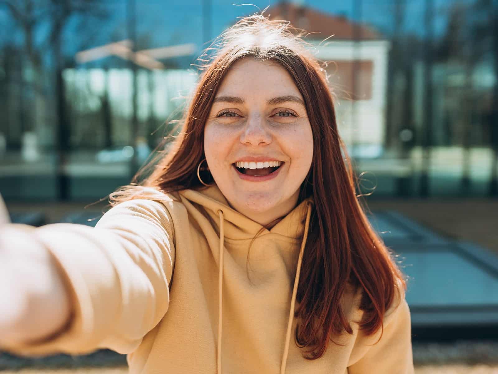 Woman taking a selfie in yellow sweater-min Woman taking a selfie in yellow sweater